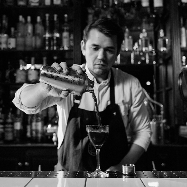 Mixologist pours signature cocktail behind bar