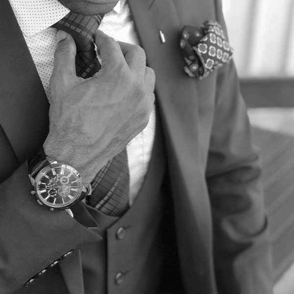 Gentleman straightens his tie wearing suit and luxury accessories 