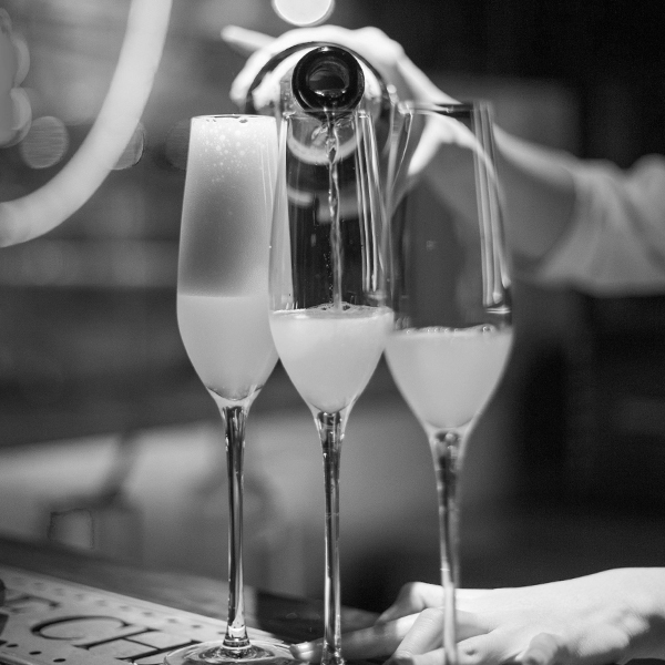 Bartender pours glass flutes with champagne